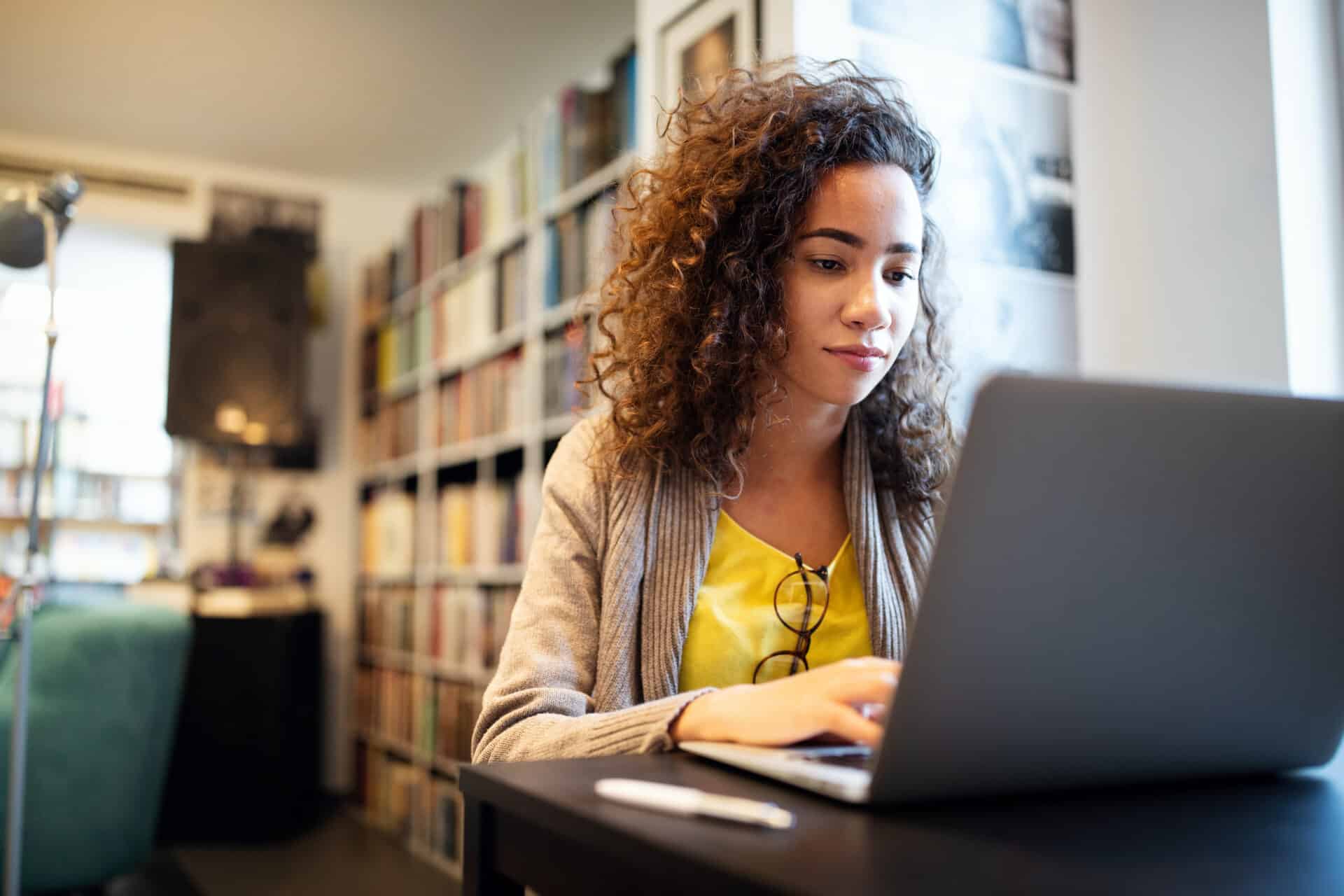 Student doing an online TEFL course on a laptop in a library