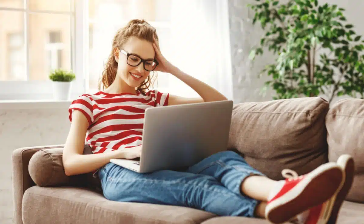Woman sitting on a couch using Google finding jobs teaching English abroad