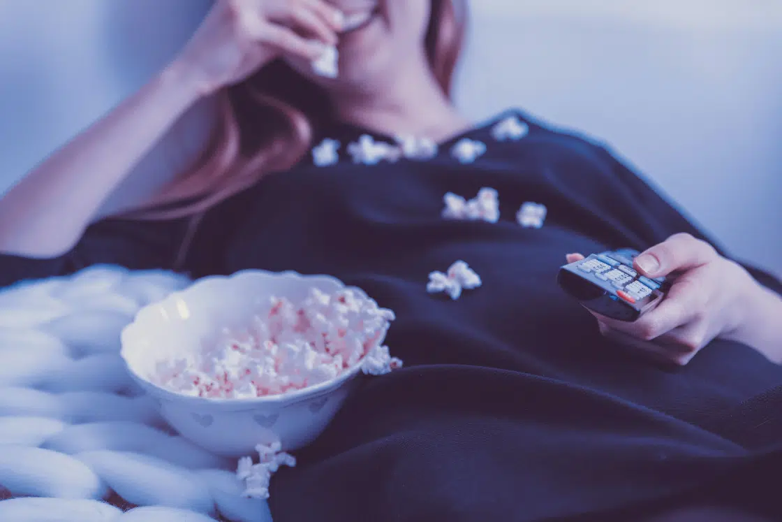 girl eating popcorn while watching tv