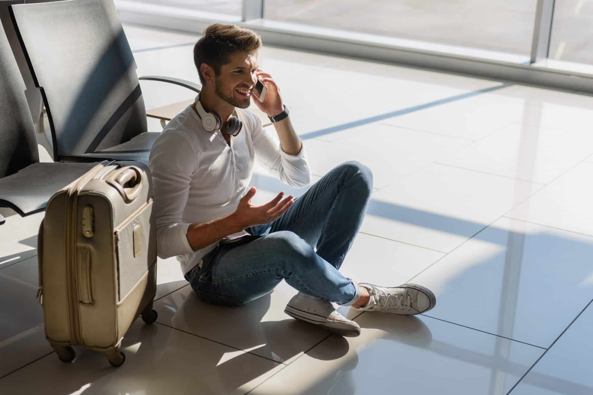 Man sitting on airport floor talking on the phone during a long layover