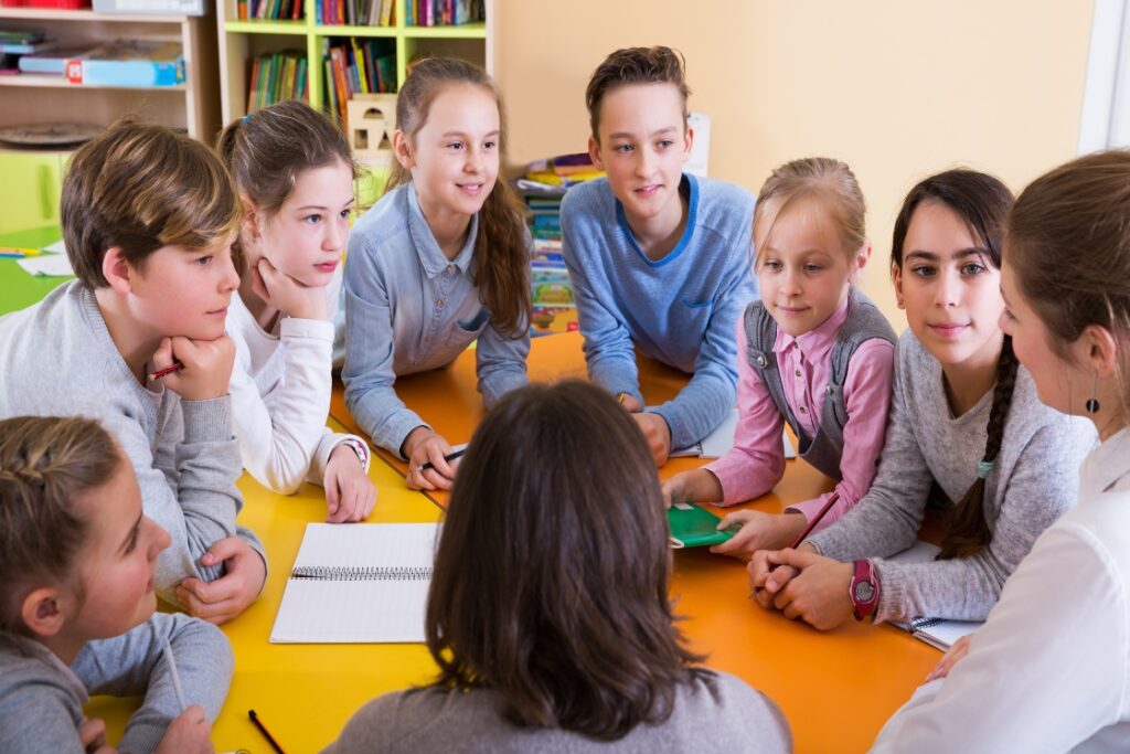 Elementary learners at a table with a teacher