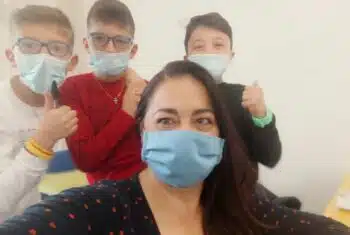 Older teacher in a mask with three students