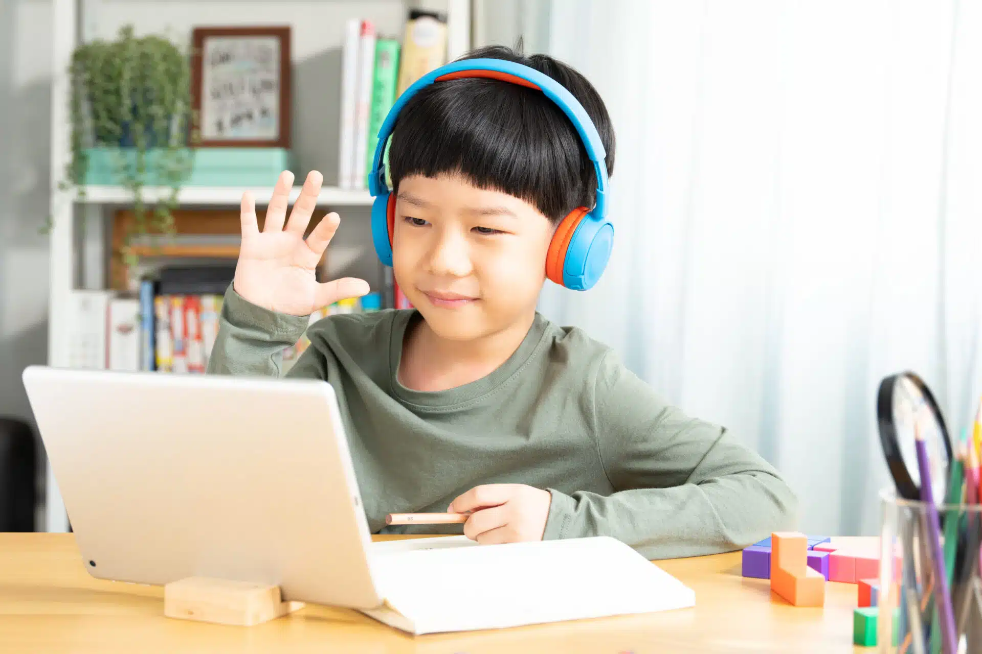 Young boy learner with headphones happily engaging in an online lesson
