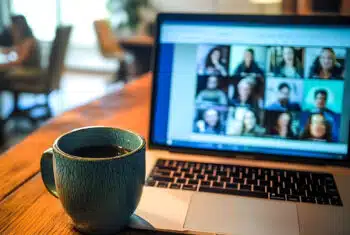 A mug on a table next to a laptop open to an online lesson