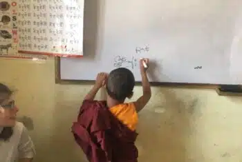 Young monk writing on a whiteboard in a monastery